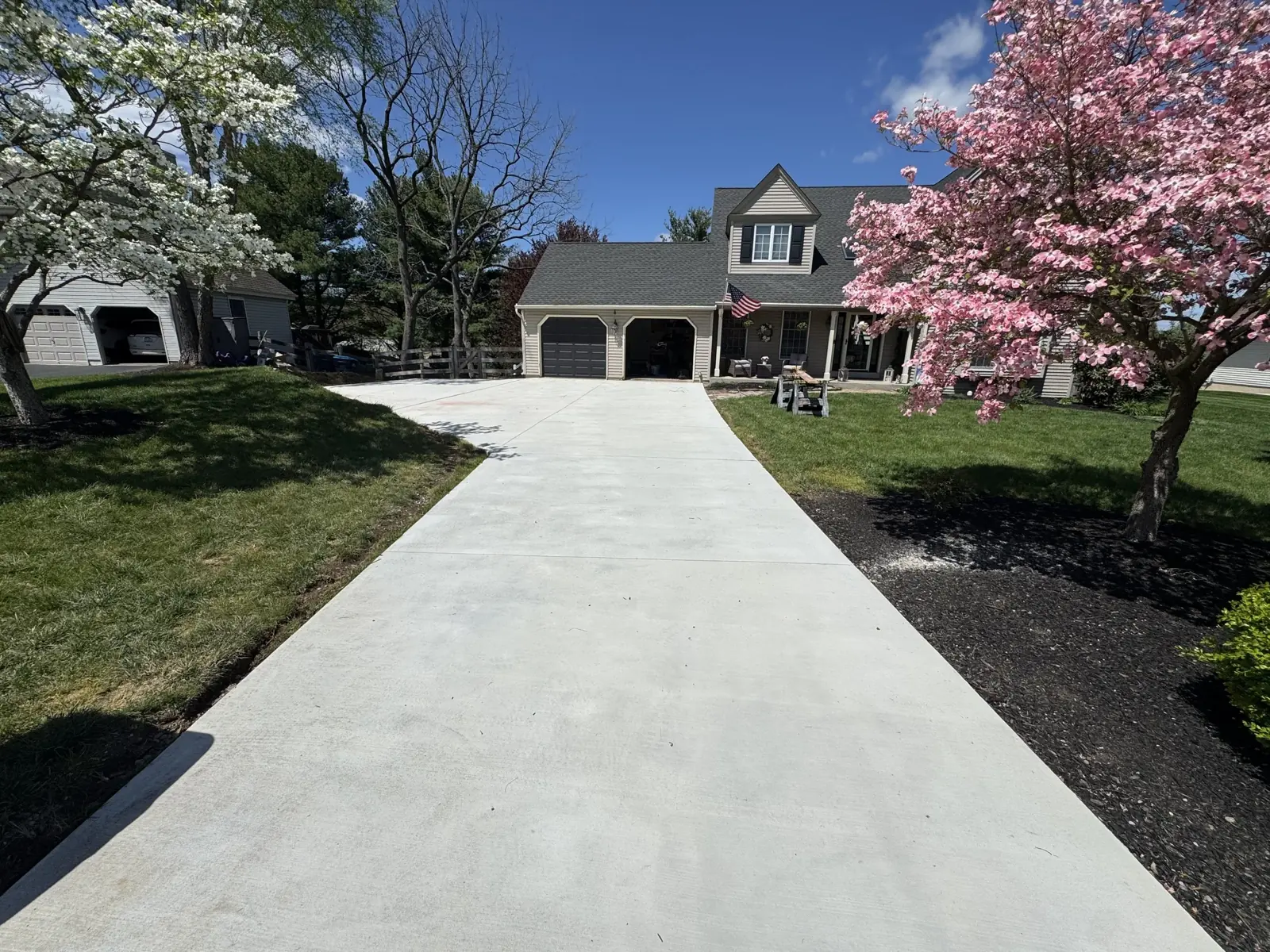 New broom-finished concrete driveway leading to a stone house
