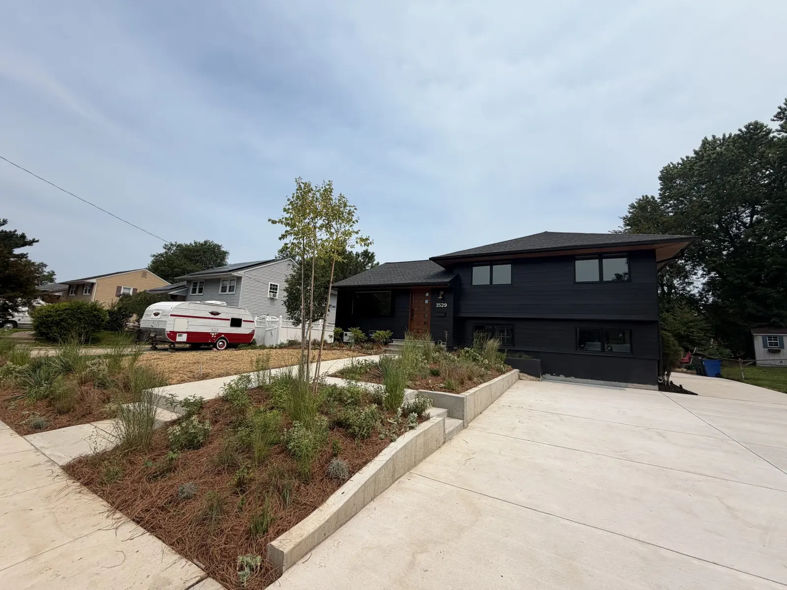 New concrete driveway and planters at a modern black house