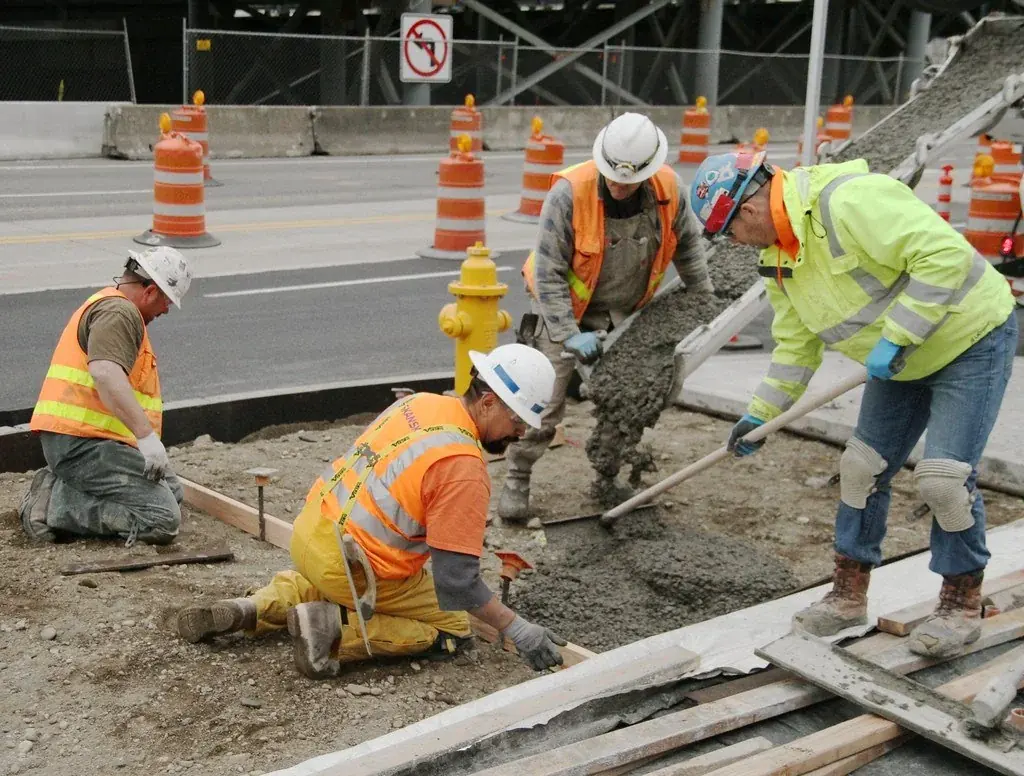 Crew screeding fresh concrete on a street-side pour