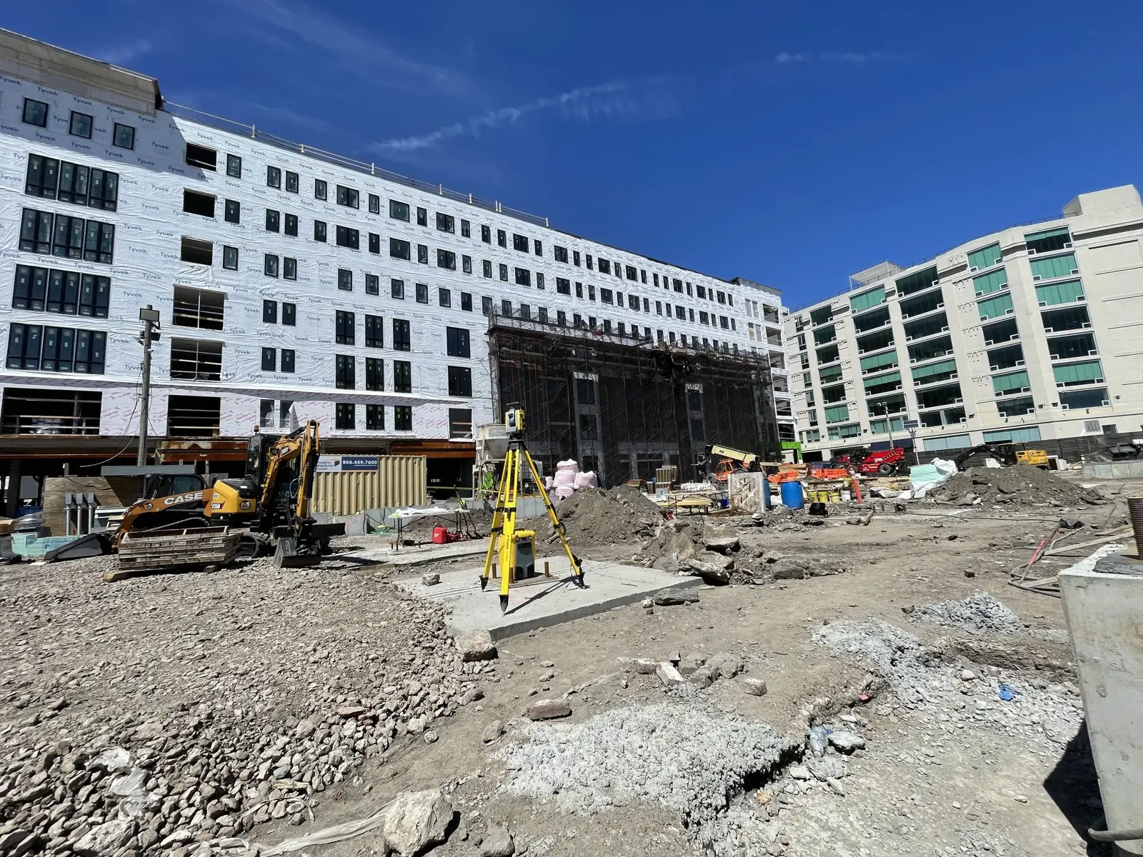 Excavator working a commercial site between mid-rise buildings